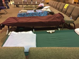 Cots lined up in a church emergency shelter